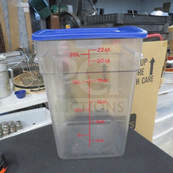 22-quart clear food storage container with blue lid, marked with quart and liter measurements, in good condition.