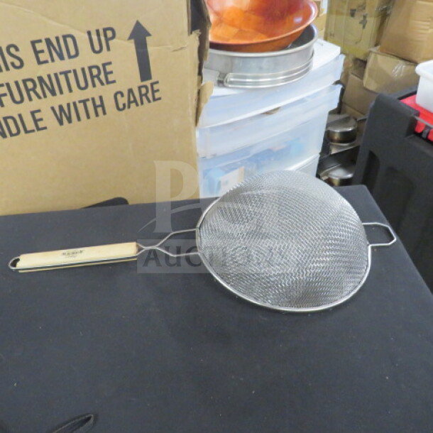 Metal mesh strainer with a wooden handle, displayed on a black surface. Appears in good condition. No visible brand markings.