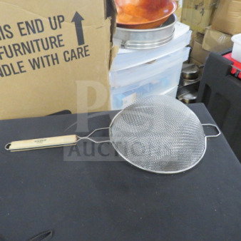 Metal mesh strainer with a wooden handle, displayed on a black surface. Appears in good condition. No visible brand markings.