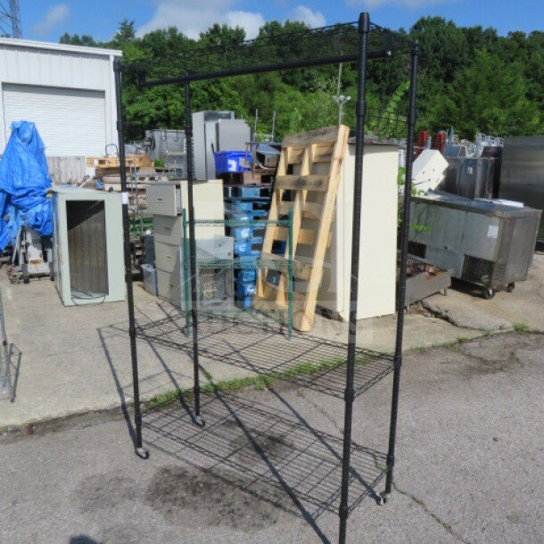 Black Metro shelf with 3 shelves, coat rack, and hooks on casters, measuring 47x18x75 inches. Sturdy and versatile storage unit.