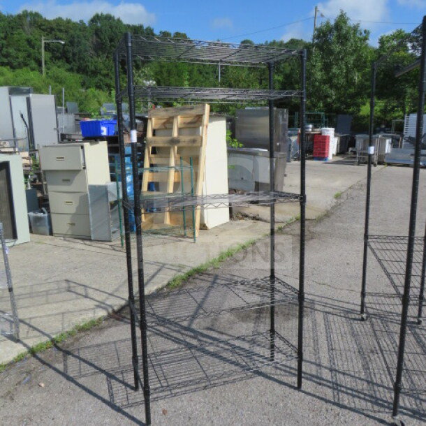 Black Metro shelf unit with five wire shelves, dimensions 36x14x74 inches, in used condition, outdoors.