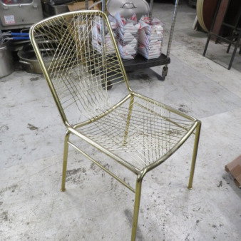 Gold metal chair with lattice design. Features a sturdy frame and sleek finish. Ideal for modern interiors. Model: 2XBID.