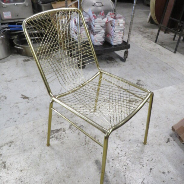 Gold metal chair with wire mesh design, showing a modern style. In good condition, suitable for indoor or outdoor use.