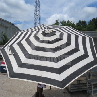 Black and white striped patio umbrella, open, in used condition, large canopy, suitable for outdoor use.