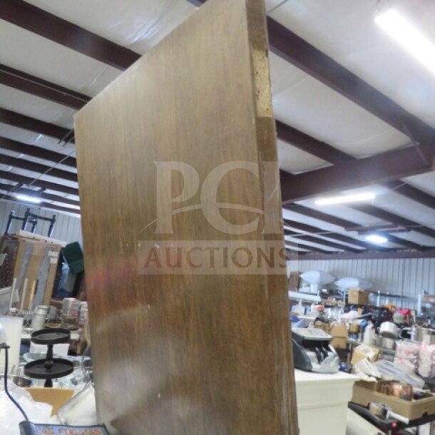 Wooden door, 36x83.5 inches, with handle. Brown finish, solid wood construction. Visible in a warehouse setting.