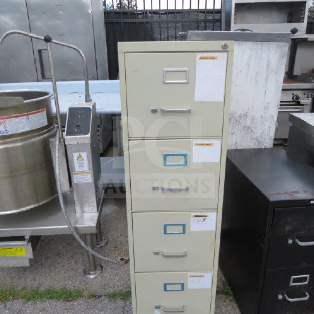 Four-drawer metal file cabinet, cream color, visible labels, minor wear, standard office size, suitable for document storage.