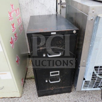 Black metal 2-drawer file cabinet, showing wear and scratches. Features silver handles and a lock on the top drawer.