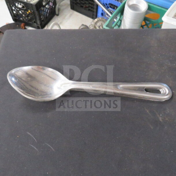 Stainless steel spoon with a sleek, polished finish. Features an ergonomic handle with a hanging hole. Model 3XBID.