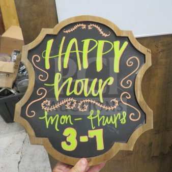 12x14 wooden framed chalkboard with decorative edges. Bright lettering says "HAPPY hour Mon-Thurs 3-7" in neon colors.