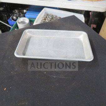 Metal 10X6 sheet pan on table. Appears in good condition with slight wear. Ideal for baking and roasting.