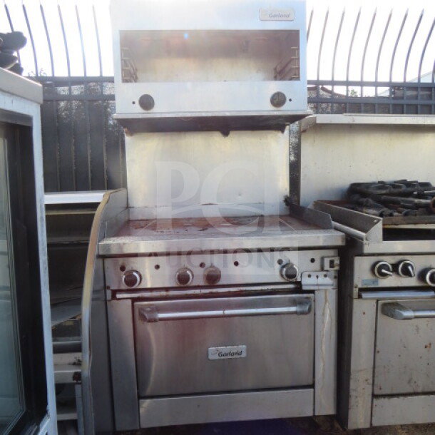 Garland natural gas range with griddle and salamander broiler overhead, includes one rack, on casters. Size: 36x35x74 inches.