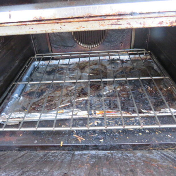 Garland griddle with salamander over, featuring a natural gas range and one rack. Measures 36x35x74, on casters. Used condition.