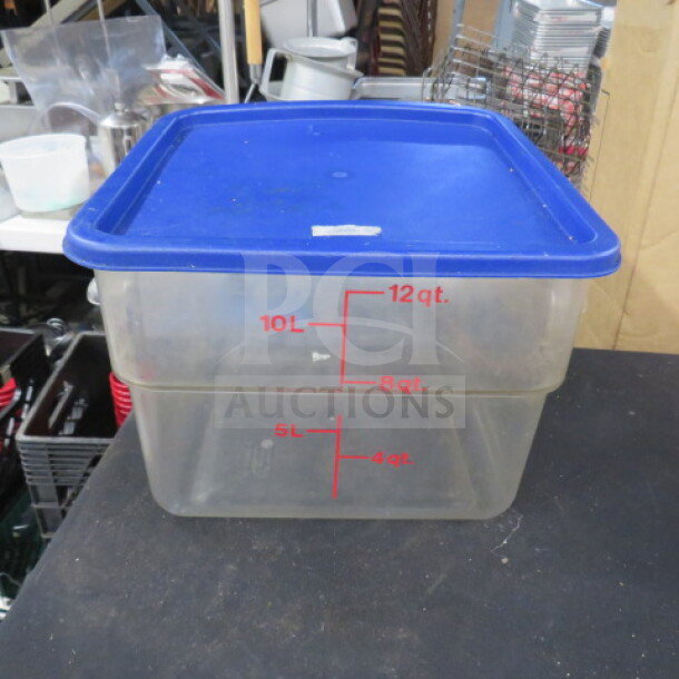 12 quart food storage container with blue lid, features volume markings for quarts and liters, shows minor wear.