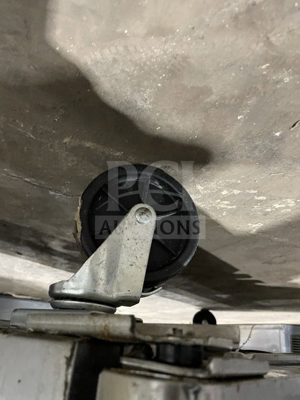 The image shows the caster wheel of a Berg Commercial 60" Stainless Steel 2-Door Prep Table, Model BERGS60.