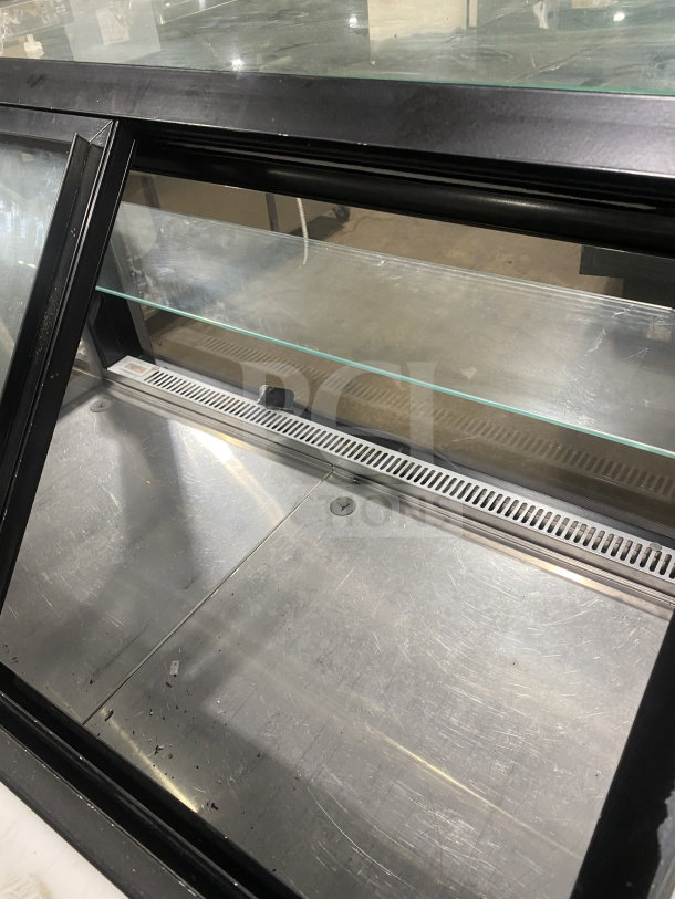Commercial display case with glass front and shelving, black trim, visible scratches on metal interior.