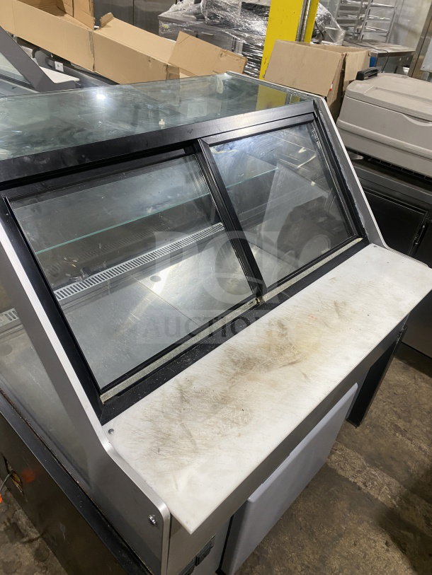 Glass display case with sliding doors and white countertop, showing signs of wear. Suitable for deli or retail use.