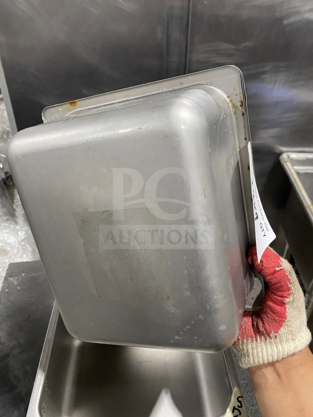 Commercial stainless steel half-size hotel food pan, showing exterior condition with minor wear. Includes bidding information tag.