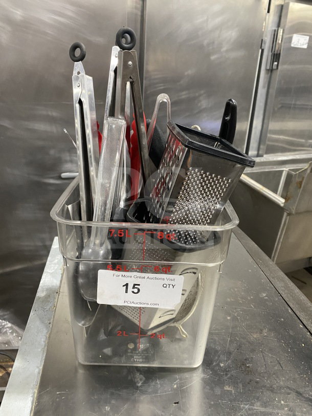 Commercial kitchen smallwares and prep utensils lot in a clear container. Includes tongs, grater, and spoons. Good condition.