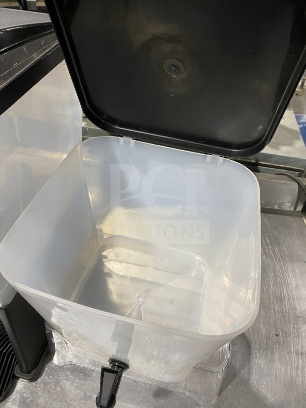 Commercial plastic cold beverage dispenser with clear reservoir, black lid, tap, and visible interior. Good condition.