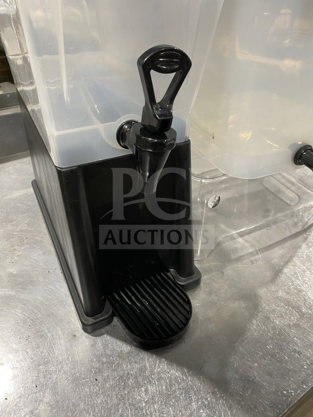 Commercial plastic cold beverage dispenser set, featuring a black base with a spout, and a clear plastic reservoir alongside.