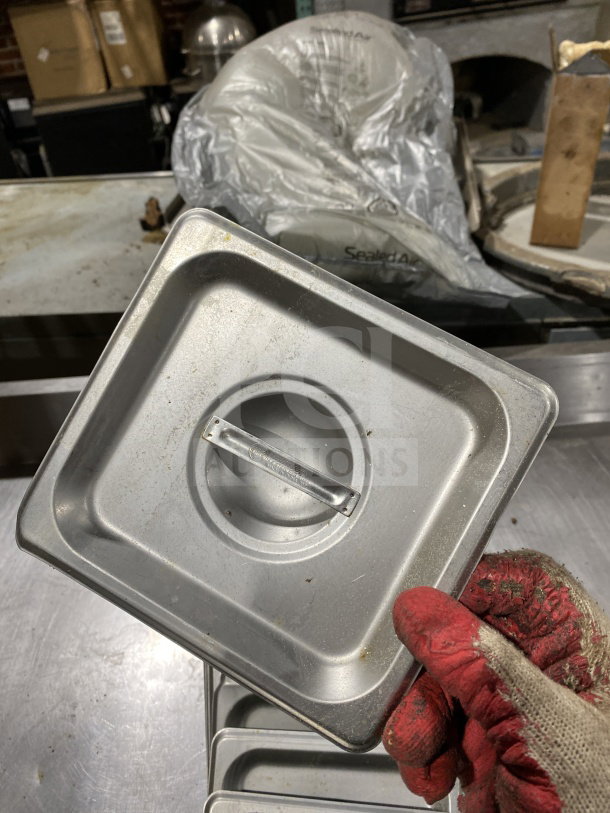 Winco stainless steel 1/6 pan lid, model SPSCS, in used condition with visible wear. Auction lot of 16.
