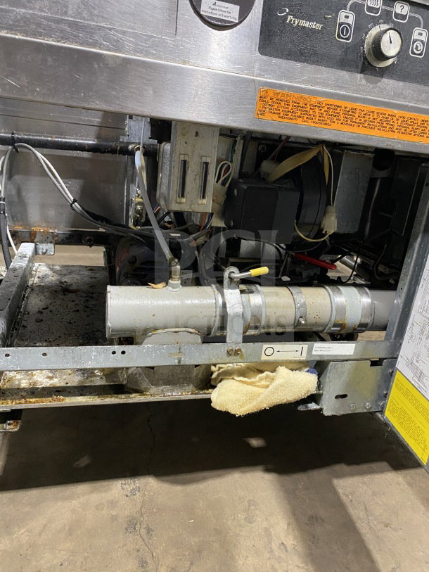 Frymaster commercial stainless steel dual deep fat fryer, model FMPH255SC. Features left dumping station, backsplash, filter system. Natural gas powered, on casters, working condition. Visible warning label and control panel.