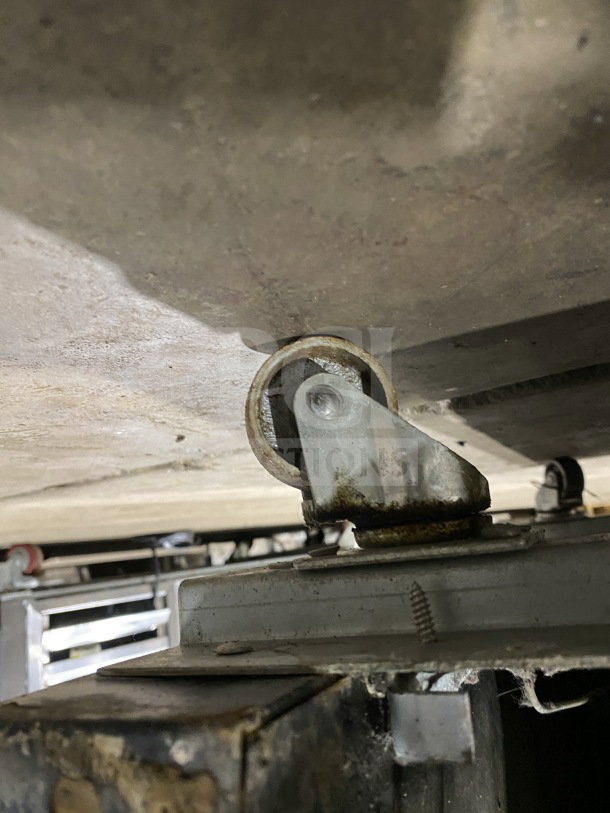 Rusted caster wheel of a Kelvinator Commercial 28" freezer model KCGM24FB, showing wear and dirt accumulation.
