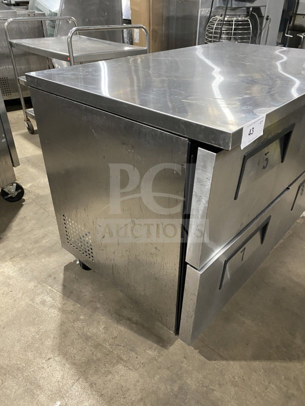 True TUC-48F-D-4-HC stainless steel 4-drawer undercounter freezer with marble-style worktop, upturned splash, and casters.