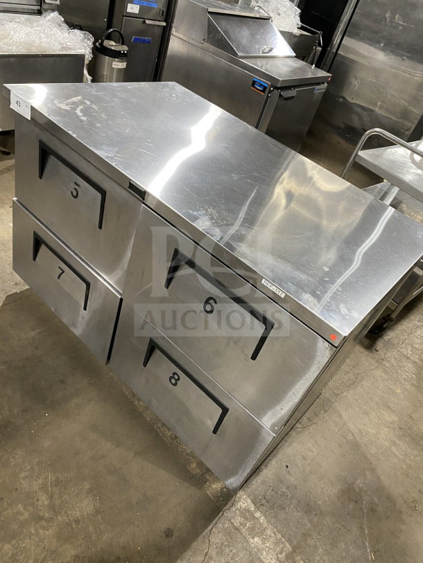 True TUC-48F-D-4-HC undercounter worktop freezer with marble style top, upturned splash, and casters. 4 stainless drawers.