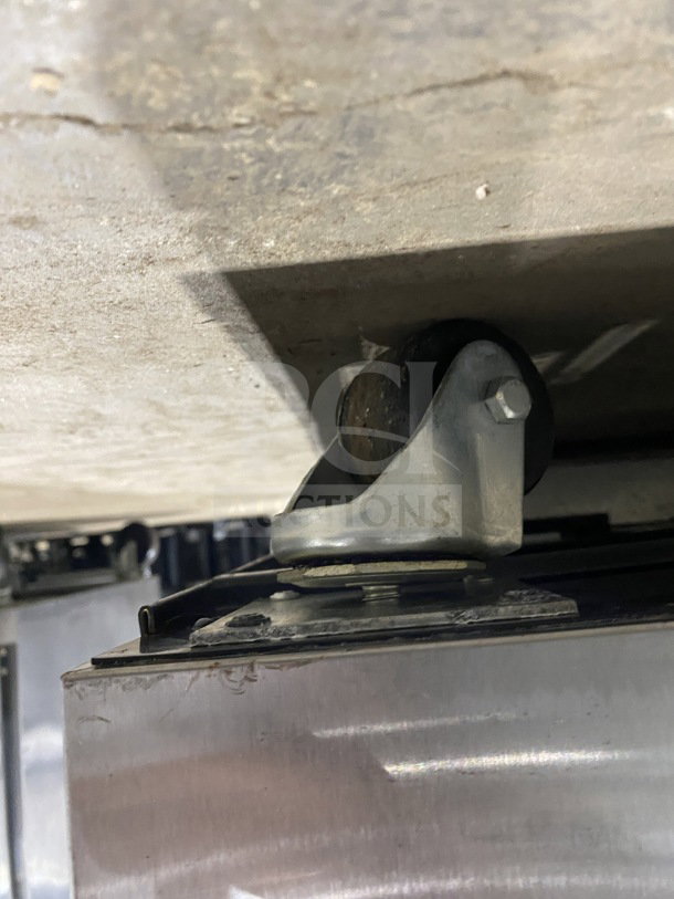 Close-up of a caster wheel on the True TUC-48F-D-4-HC stainless steel worktop freezer with marble finish.
