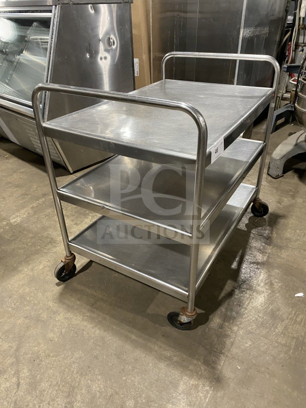 Commercial stainless steel utility trolley with three compartments, mounted on casters for easy mobility.