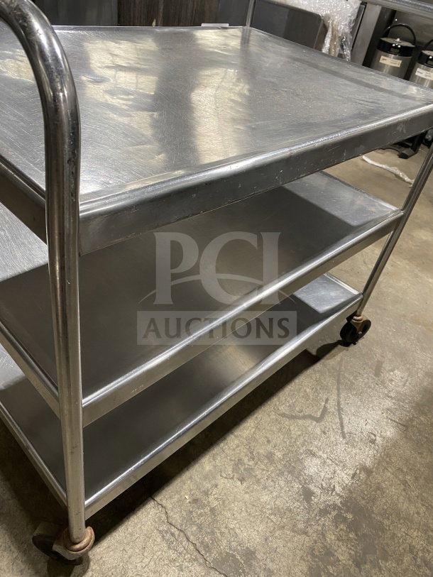 Commercial stainless steel utility trolley with three compartments on casters, showcasing a durable design and smooth finish.