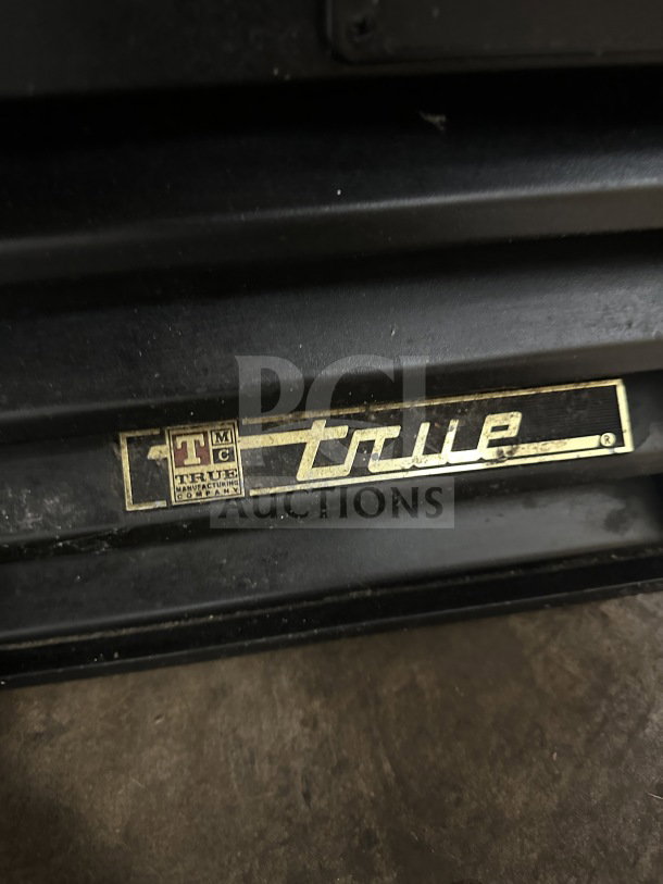 True Commercial Coca-Cola style black glass-door merchandiser, Model GDM-26EM, with poly coated wired rack. Visible True logo.