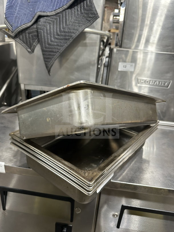 Commercial stainless steel steam table pans, stack of five, used condition, durable and ideal for catering.