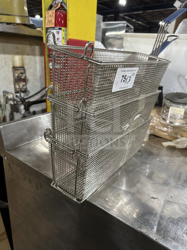 Commercial stainless steel deep fryer baskets with blue vinyl heat-resistant handles. Includes label indicating auction details.