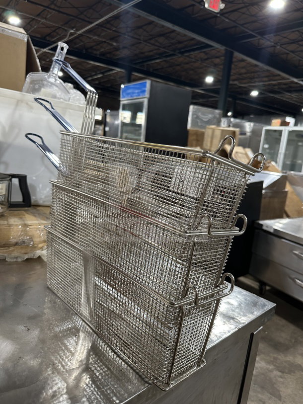 Commercial stainless steel deep fryer baskets with blue vinyl heat-resistant handles, shown stacked. Excellent condition.