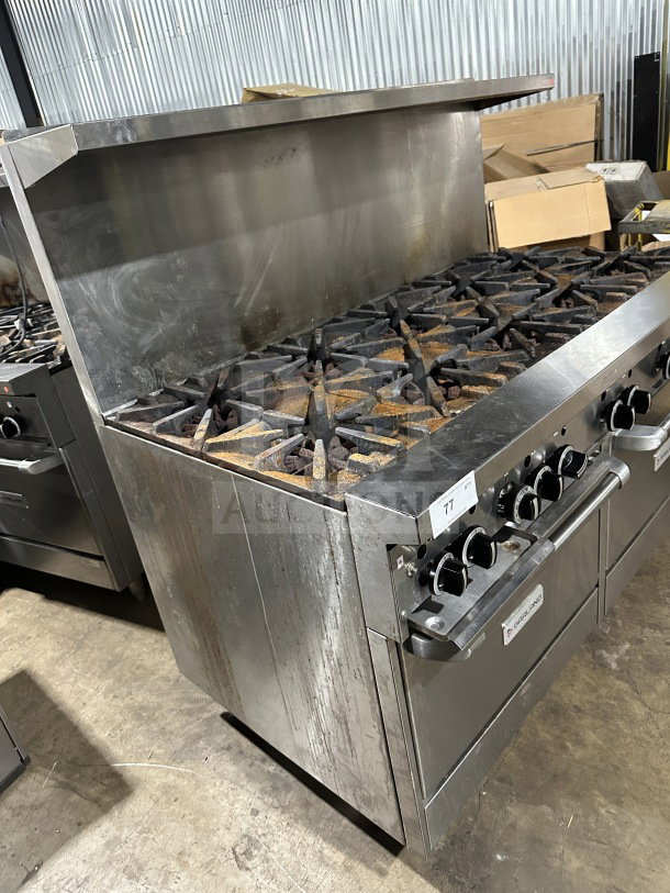 Garland commercial stainless steel 10-burner range with double oven and backsplash. Includes wired oven rack, on legs. Visible wear.