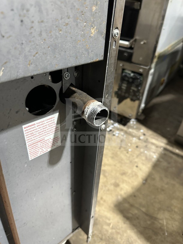 Garland commercial stainless steel gas range back view, showing pipe connection and warning label.