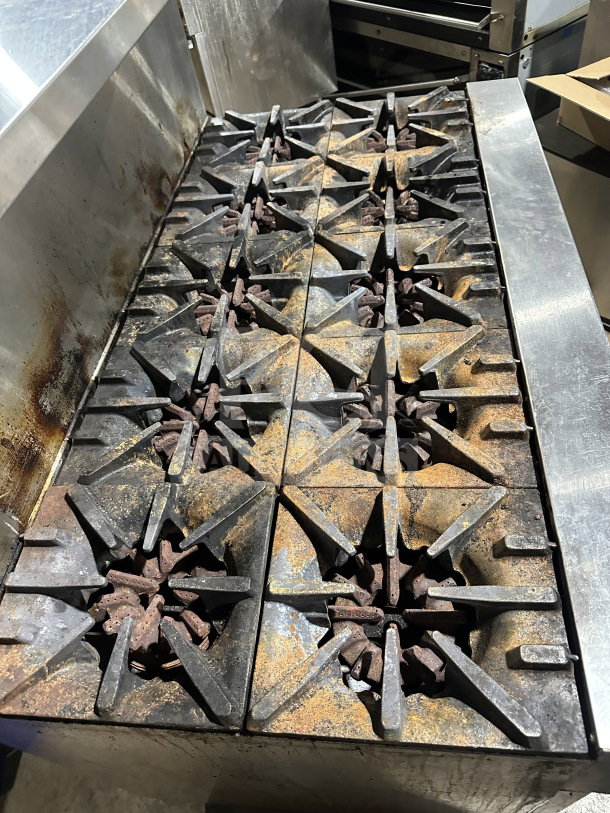 Garland stainless steel 10-burner gas range with double oven, backsplash, wired oven rack, on legs; used condition.