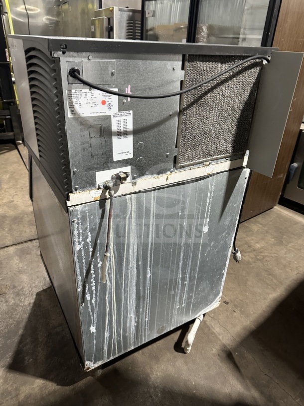 Manitowoc SY0304A stainless steel ice machine, air-cooled, on legs, electric powered, used condition, visible serial and spec labels.