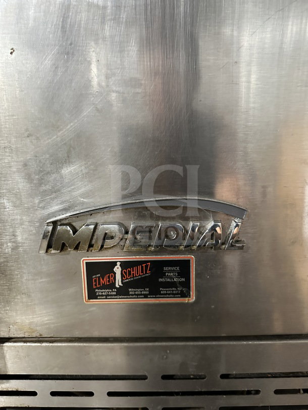 Imperial stainless steel gas-powered double convection oven, features wired rack, on casters. Elmer Schultz service label visible.