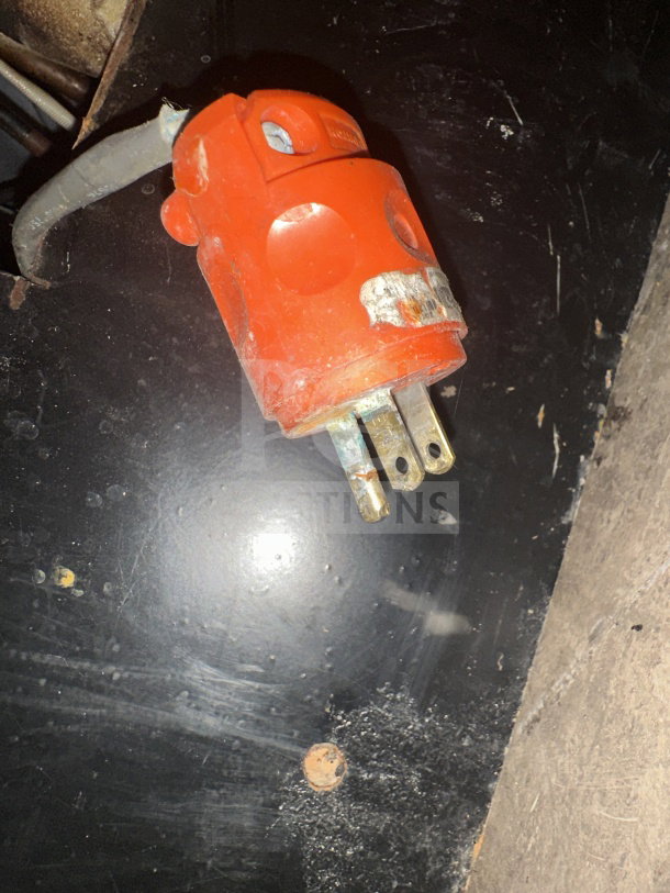 Red electrical plug on a black background, possibly from a Senkar refrigerated display case. Plug shows signs of wear.