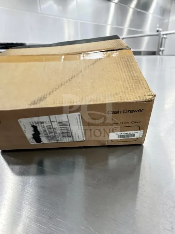 Pristine Toast TC200 POS cash drawer in a brown box, labeled with model details, lockable, printer-driven, new condition.