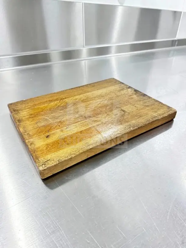 Large maple butcher block cutting board, 24"x18", commercial grade, with non-slip feet, showing signs of use, ideal for chefs.