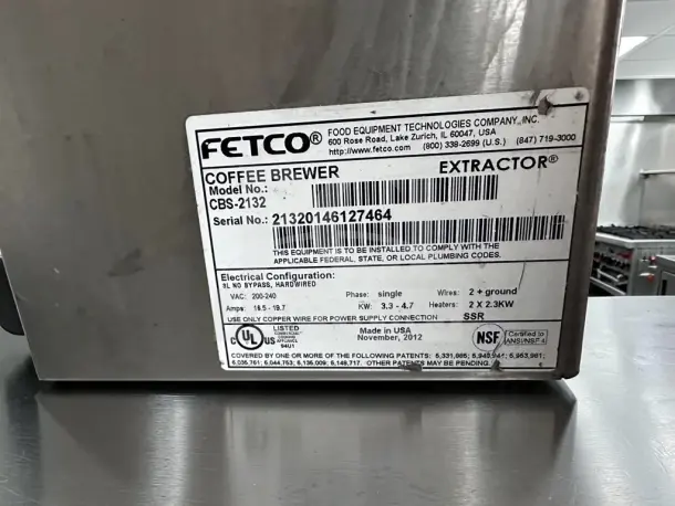 FETCO CBS-2132XTS stainless steel coffee brewer, model tag showing electrical specs, serial number, and manufacturing info.