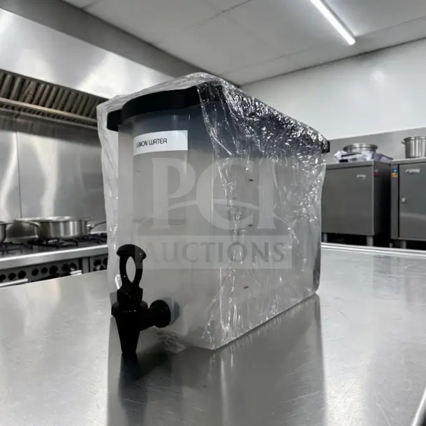 Like-new plastic cold juice dispenser with spigot, labeled "Lemon Water,” in a commercial kitchen setting.