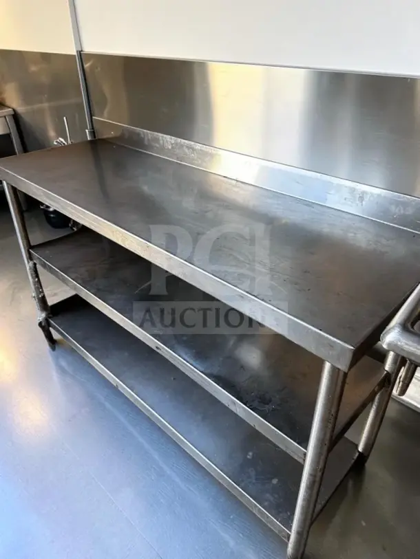 Stainless steel commercial work table, 55" × 17", with two undershelves and backsplash, fully inspected, ready for use.
