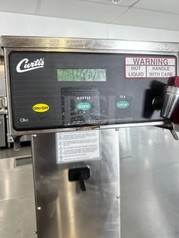 Wilbur Curtis CBS10000 brewer in exceptional condition. Features coffee, iced coffee, and tea options. Includes adjustable shelf and warning label.