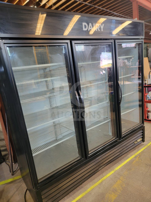 True GDM-72-HC 3-Door Glass Merchandiser Refrigerator, black, excellent condition, "DAIRY" label, spacious shelves.