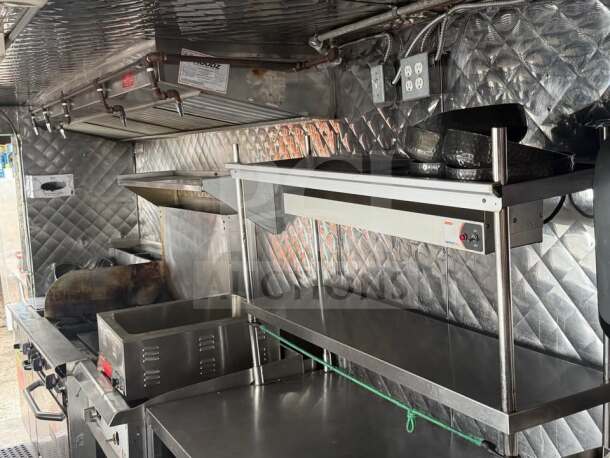 1999 Chevrolet P30 food truck interior with stainless steel commercial kitchen, including grill, fryer, and warming shelf.